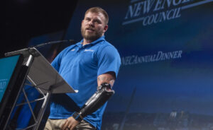 Travis Mills speaking on podium, lifestyle
