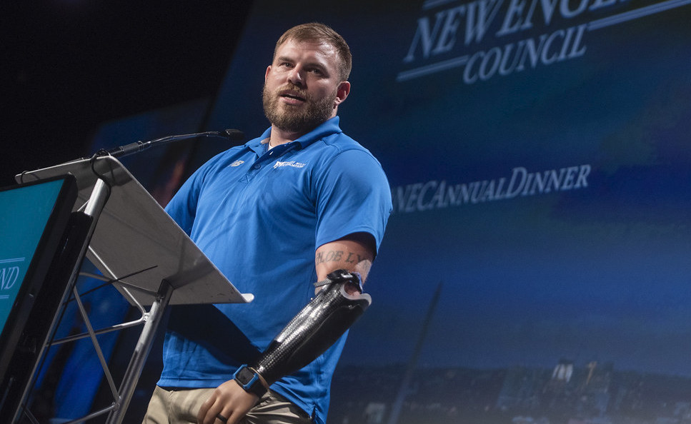 Travis Mills speaking on podium, lifestyle